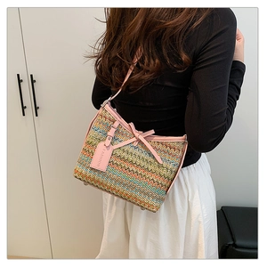Detail view of woven shoulder bag with pink bow accents and multi-color wavy pattern texture