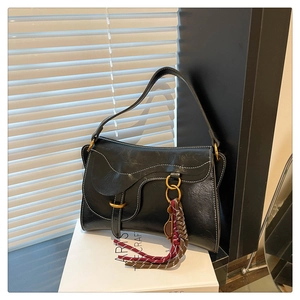 Detail of vintage black leather saddle bag featuring contrast white stitching and gold hardware