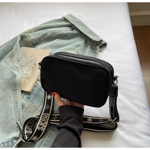 Detail of black camera bag with printed slogan and wide jacquard woven SJCHAO strap