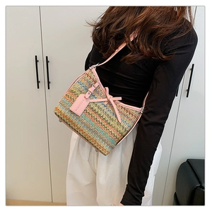 Detail of woven straw shoulder bag with pink leather strap and decorative bow