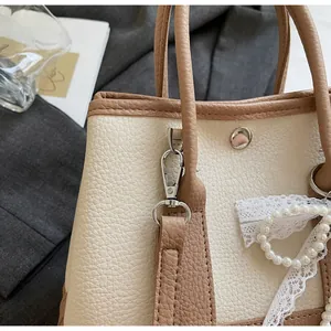 Detail of lychee pattern leather bucket bag with pearl lace bow and metal buckle