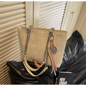 Detail of off-white tote bag featuring silver chain strap and fashion logo text