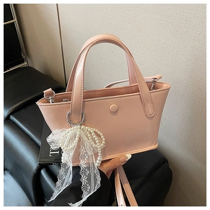 Dettaglio della borsa rosa in ecopelle con ciondolo a perla e fiocco in pizzo