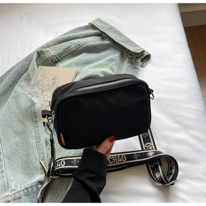 Detail of black canvas camera bag with floral print wide strap and silver zipper
