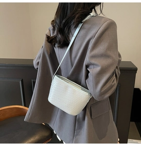 Detail of mint green woven texture crossbody bag shown styled with a grey blazer outfit