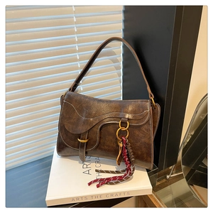 Macro detail of dark brown saddle bag with contrast stitching and golden ring hardware