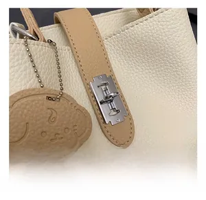 Detail of lychee pattern leather bag with silver rotary lock and dog charm decor