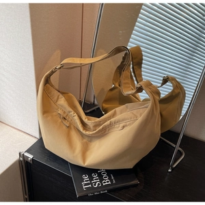 Detail view of khaki nylon crescent bag on a sleek black table in a minimalist home setting