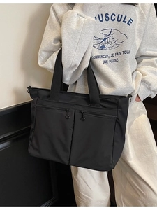 Minimalist black nylon tote bag with dual front zippers and versatile shoulder strap