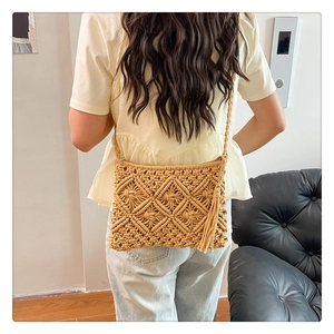 Model wearing a beige macrame shoulder bag with fringe details and woven strap