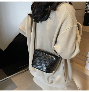 Rear view of a model wearing a black woven leather shoulder bag with Intrecciato pattern