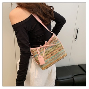 Detail of colorful woven shoulder bag with pink leather bow and fashion tag hanging on side