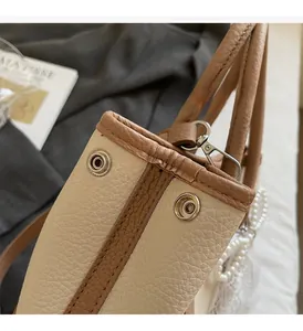 Detail of lychee pattern leather bucket bag with silver hardware and pearl chain