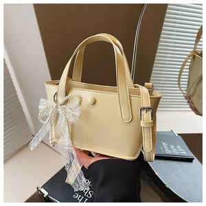 Dettaglio borsa giallo chiaro in pelle liscia con fibbia decorativa e ciondolo in pizzo e perle