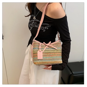 Detail of colorful woven shoulder bag featuring pink leather trim and a chic bow detail