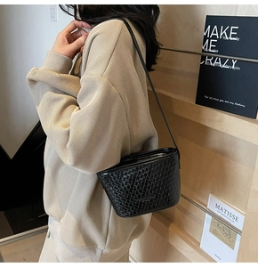 Detail of a black woven leather shoulder bag showing the premium texture and strap