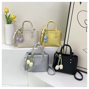 Detail view of four minimalist mini bucket bags in beige, yellow, silver and black colors