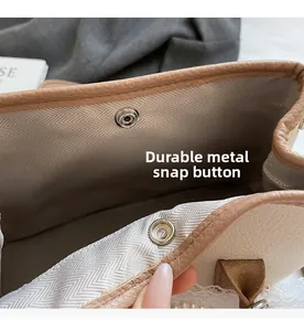 Detail of silver metal snap button and herringbone fabric lining on a canvas tote bag