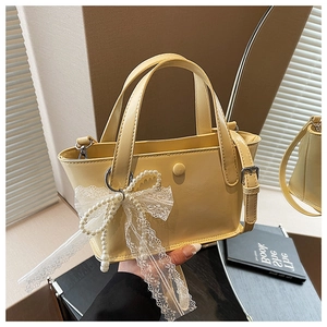 Dettaglio mini borsa a secchiello in vernice lucida con fiocco di pizzo e perle