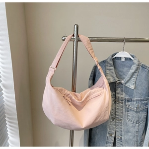 Close-up of pink crescent shoulder bag with zipper pocket and adjustable strap detail