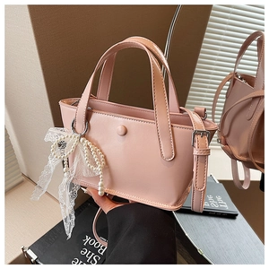 Dettaglio borsa in pelle PU rosa con fiocco in pizzo bianco e ciondolo di perle eleganti