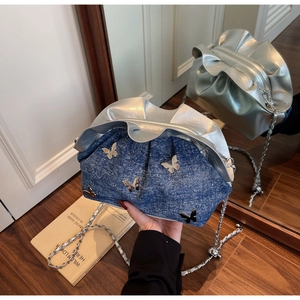 Detail of blue denim shoulder bag with silver 3D butterflies and chain strap