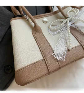 Detail of lychee textured leather contrast bag with pearl bow and lace ribbon