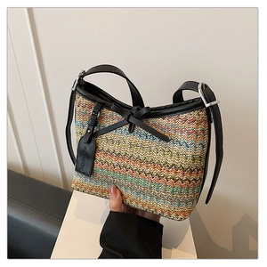 Close-up of woven straw handbag with colorful wave pattern and black leather bow detail