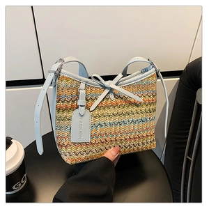 Macro detail of multi-color woven straw handbag with light blue leather bow and fashion tag
