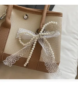 Detail of canvas garden bag with lychee leather texture and pearl lace bow charm