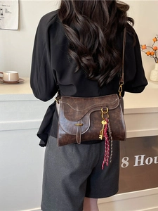 Vintage dark brown saddle bag with horsebit detail and woven tassel on a casual model