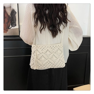 Detail view of a white macrame shoulder bag with geometric patterns and long tassels
