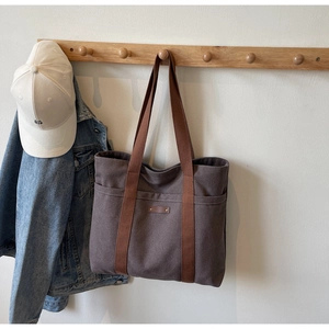 Détail du sac cabas en toile marron foncé avec sangles et deux poches frontales