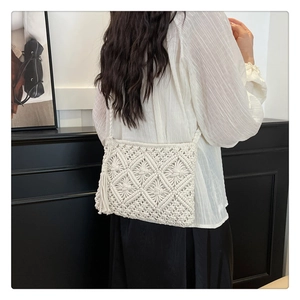 Detail of cream handmade crochet bag with geometric knit patterns and fringe tassel