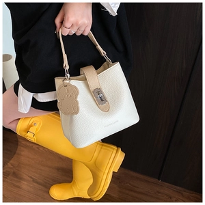 Dettaglio della borsa a secchiello in pelle martellata bianca con manico beige e ciondolo