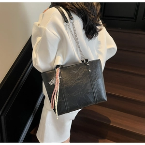 Detail of black tote bag with wrinkled PU leather texture and silver chain strap