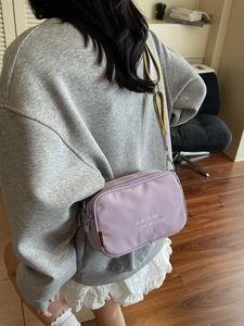 Minimalist light purple canvas camera bag with yellow strap worn by a model