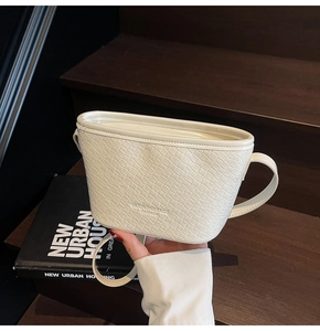 Detail of white woven texture bucket bag with embossed logo on a wooden step background