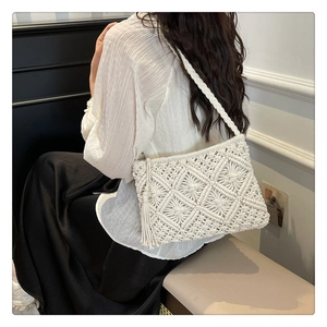 Detail of hand-woven ivory crochet bag featuring diamond patterns and side tassels