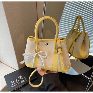 Detailed view of yellow and white litchi pattern bucket bag with pearl lace bow