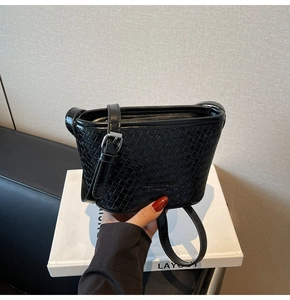 Detail of black woven texture on bucket bag with silver buckle and leather strap