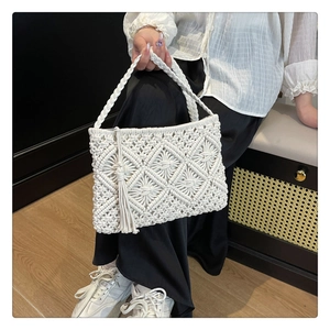 Detail view of white macrame tote bag with decorative tassels and handmade woven texture