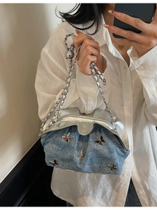 Light blue denim handbag with silver butterfly accents and chain strap on white shirt