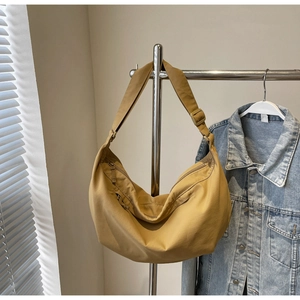Detail of mustard yellow crescent crossbody bag with wide shoulder strap and zipper pocket