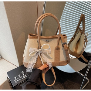 Detailed shot of beige leather bucket bag with pearl bow, lace trim, and handle