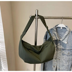 Detail view of olive green crescent shoulder bag in nylon material hanging on a metal rack