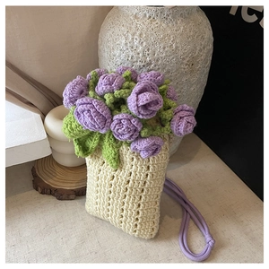 Dettaglio della borsa a secchiello in maglia crema con rose viola all'uncinetto e lacci