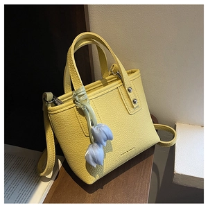 Detail of yellow lychee leather handbag featuring blue tulip charm and silver rivets