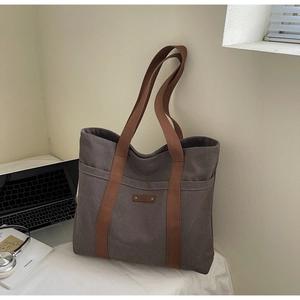 Detail of spacious charcoal canvas tote bag with brown straps and office essentials