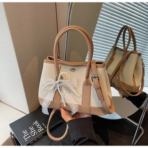 Detail of cream and brown crossbody bucket bag featuring pearl bow and lace trim decor